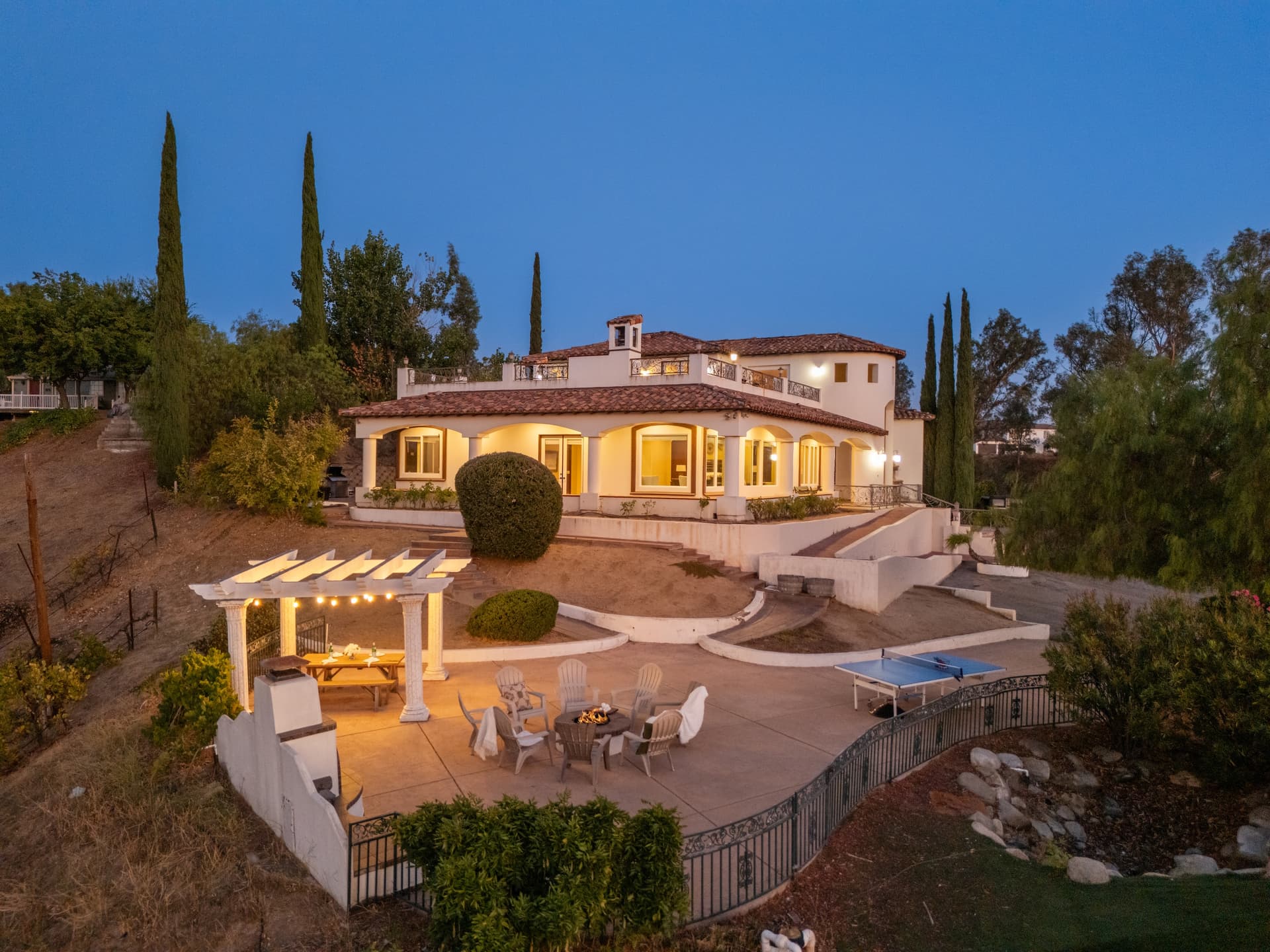 Luxury short-term rental property managed by AvantStay featuring a Mediterranean-style villa with hillside views, outdoor fire pit, pergola dining area, and spacious patio.